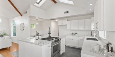 Bright modern kitchen with white cabinets and marble countertops.