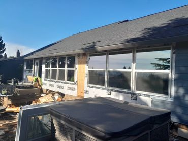 House under renovation with new windows installed and construction materials outside.