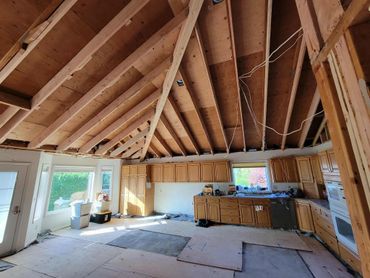 Kitchen under renovation with exposed ceiling beams and cabinets.