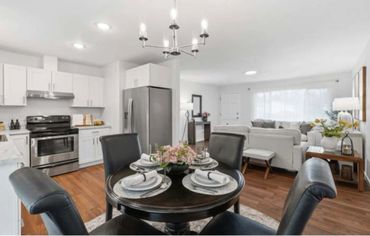 Modern open kitchen and living room with black dining table and white sofas.