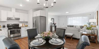 Modern open kitchen and living room with black dining table and white sofas.