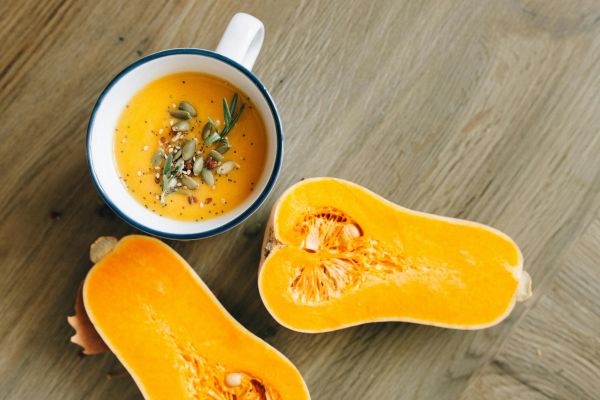 Soup in a cup with pumpkin halves.