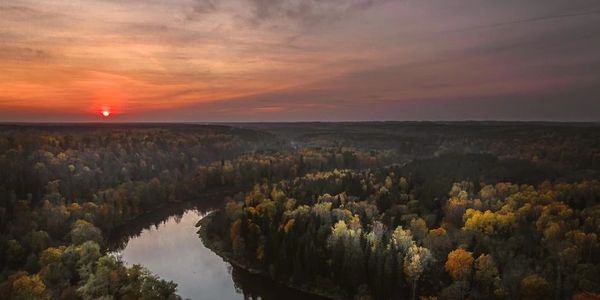 Sunset over a winding river surrounded by autumn forest.