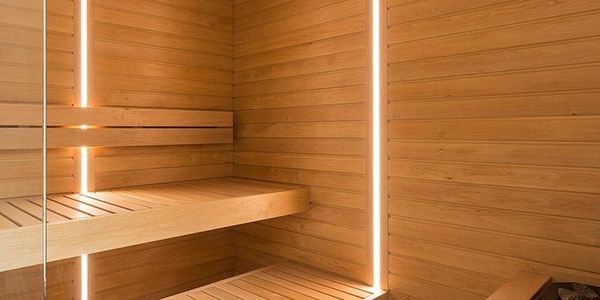 Modern wooden sauna with warm vertical LED lighting and tiered benches.