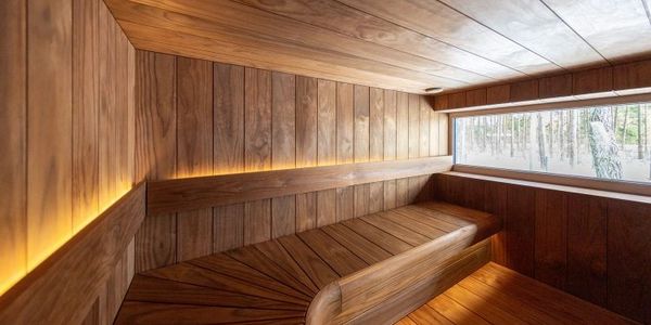 A modern wooden sauna with soft lighting and a window overlooking trees.