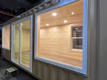A modern container home with large windows and wooden interior.