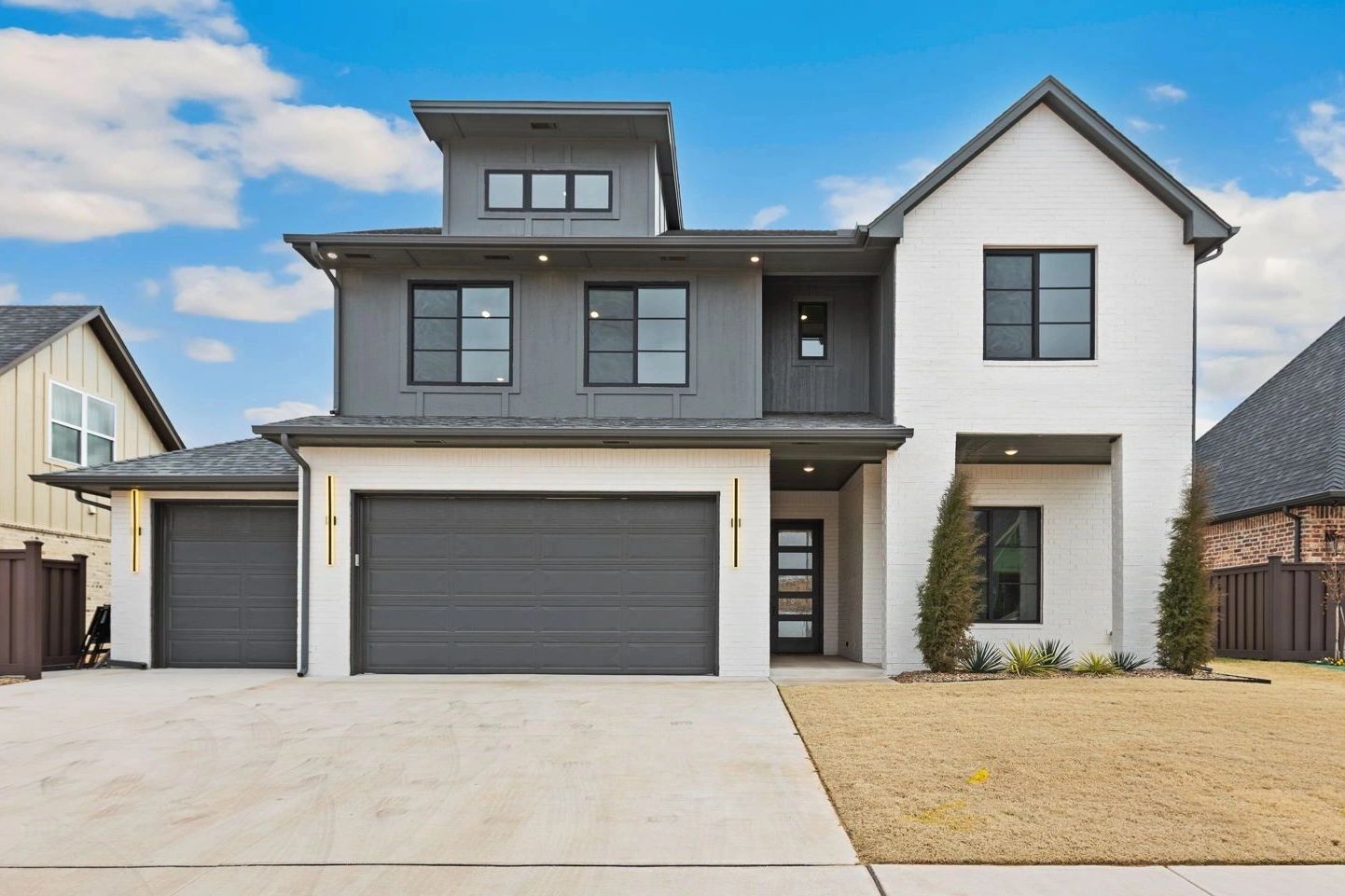 Modern two-story house with gray and white exterior and large garage doors.