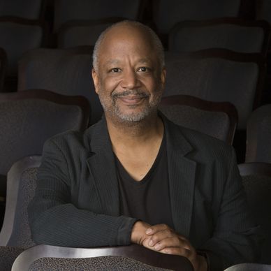 Man sitting and smiling in a theater or auditorium.