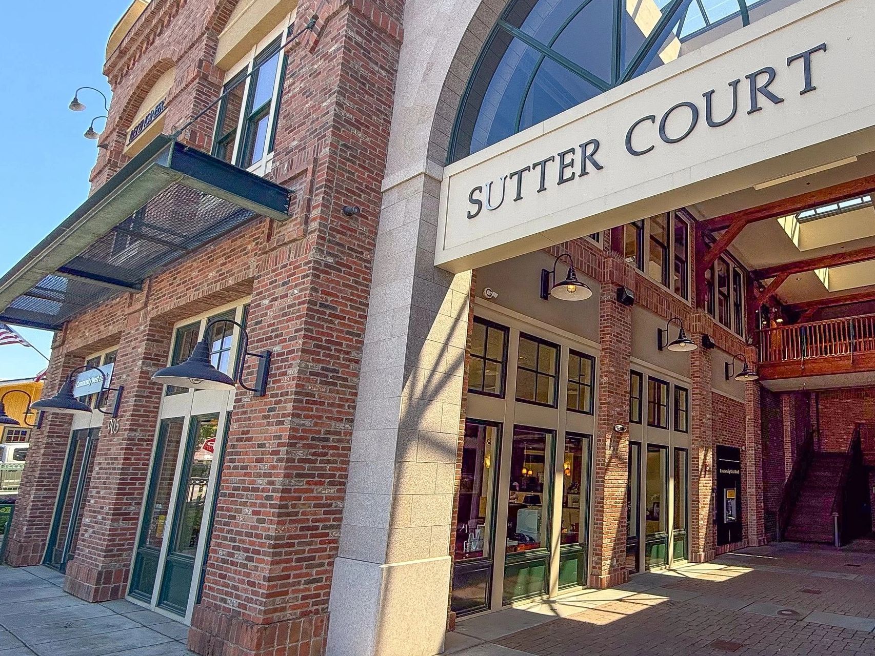 Entrance of Sutter Court with brick walls and large windows.