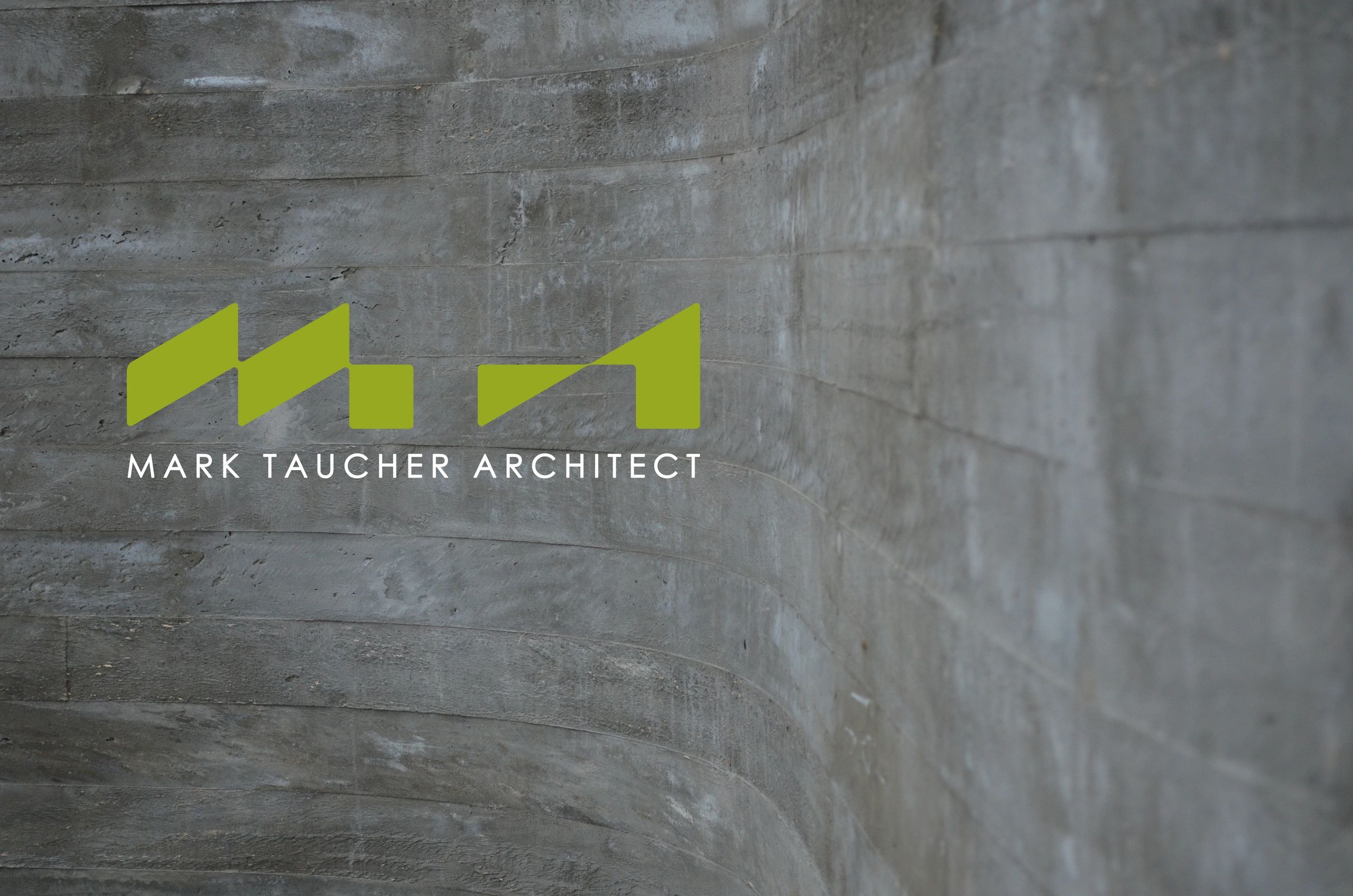 Logo of Mark Taucher Architect on a textured concrete wall.
