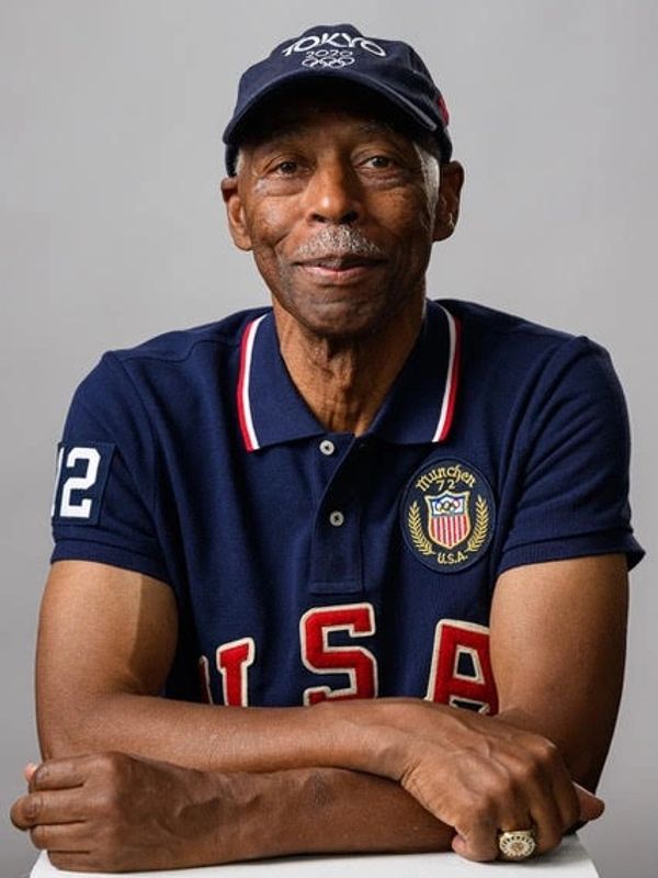 Elderly man in a USA polo shirt and Tokyo 2020 Olympics cap.
