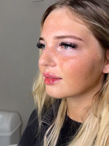 Close-up of a woman with glossy lips and long eyelashes.