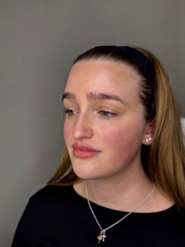 Young woman with light makeup looking sideways against a plain background.