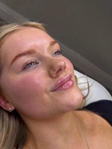 A woman with glossy lips reclining and smiling slightly.