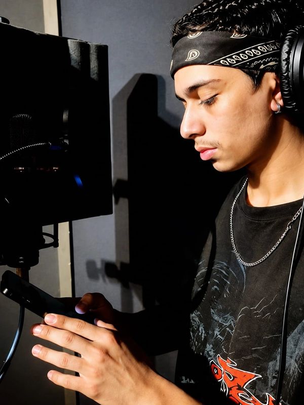 Young man with headphones and bandana in a recording studio using a smartphone.