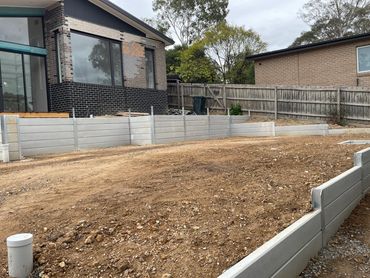 Smooth plain concrete sleeper retaining wall with fence cleats welded on top ready for a fence insta
