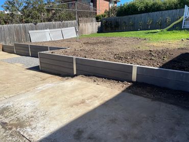 Smooth charcoal coloured concrete sleeper retaining wall 
