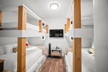 Cozy bunk bed room with wood accents and mounted TV.