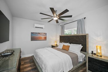 Modern bedroom with a large bed, ceiling fan, and minimalist decor.