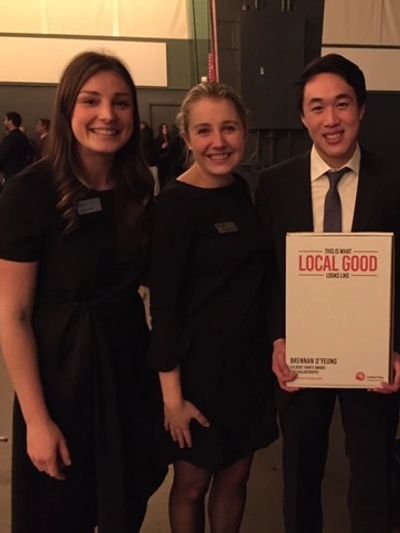Three people smiling, one holding a Local Good award plaque.