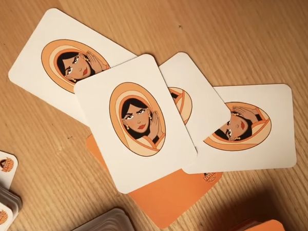Cards with illustrations of a woman in an orange headscarf on a wooden surface.