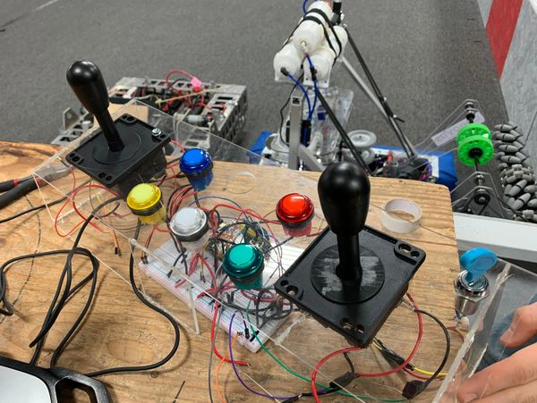DIY arcade joystick controller with colorful buttons and visible wiring on a wooden table.