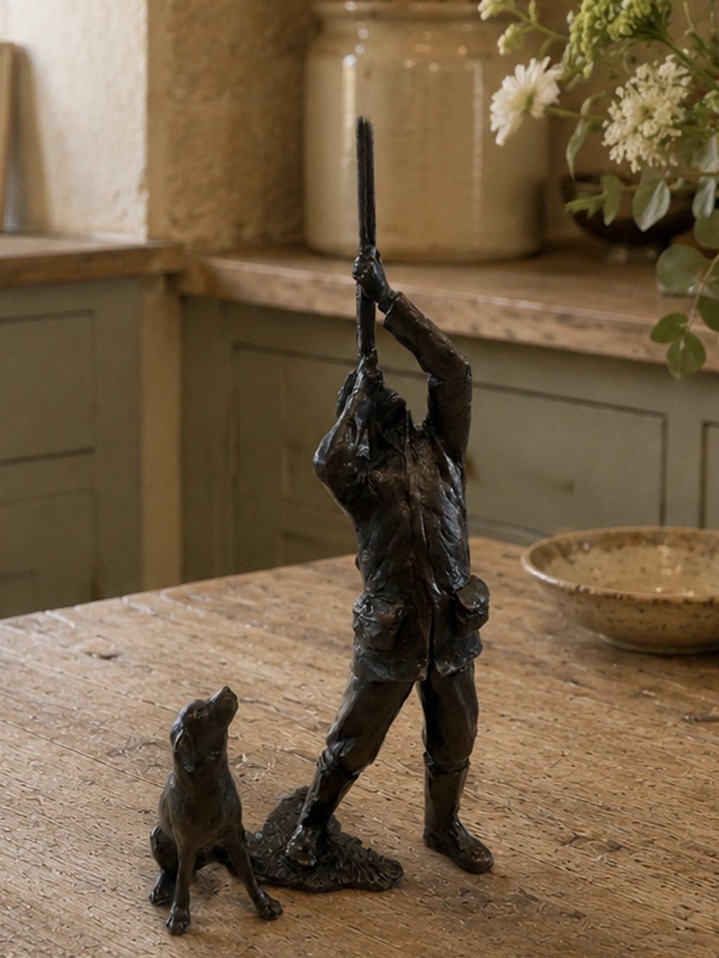 Bronze sculpture of a hunter aiming a rifle with a dog sitting beside him.
