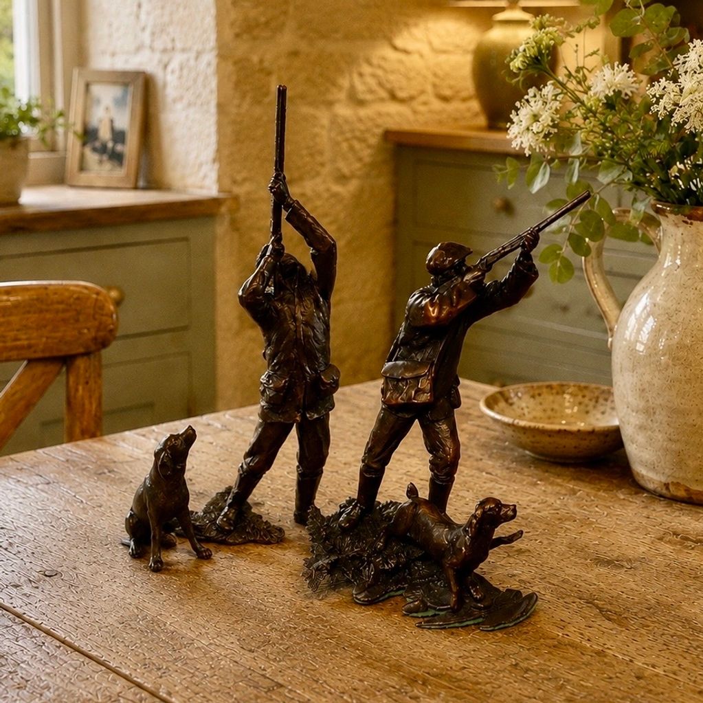 Bronze statues of hunters and dogs on a wooden table in a cozy room.