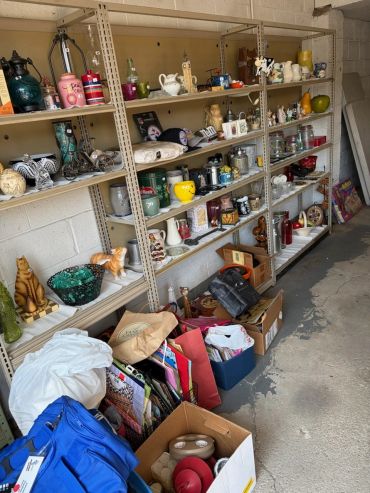 Shelves filled with assorted household items and boxes on the floor.