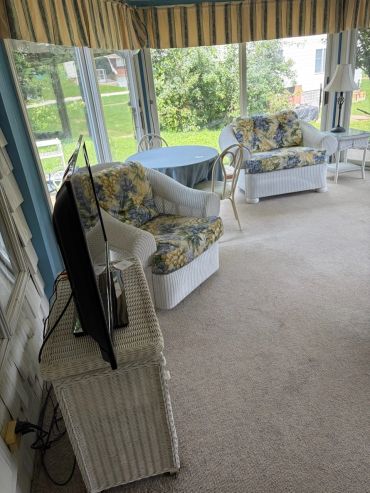 Sunroom with wicker furniture and TV.