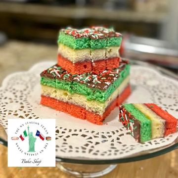 Tri-colored layered cake squares on a decorative plate with sprinkles.