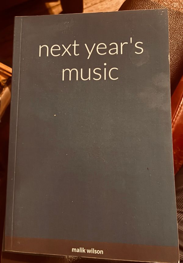 Book titled 'next year's music' by malik wilson on a dark cover.