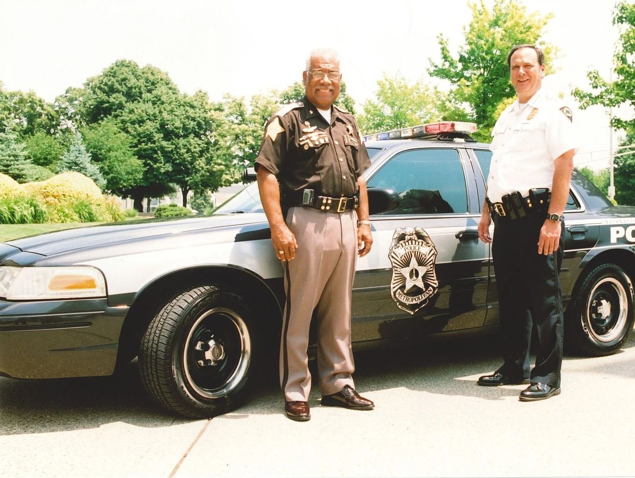Two police officers standing by a patrol car.