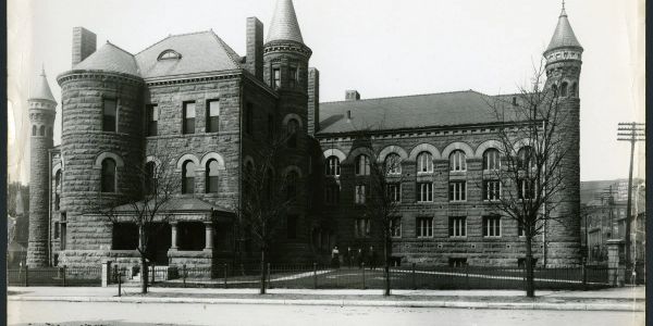 Black and white photo of a historic stone building with towers.