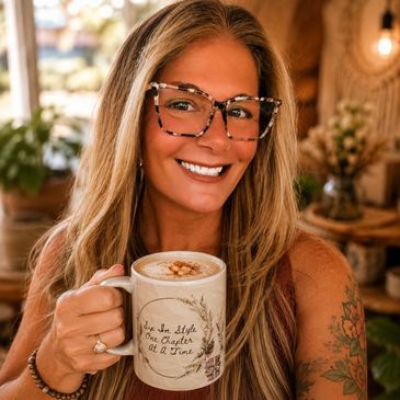 Smiling woman holding a cozy aesthetic coffee mug indoors, featuring a book-inspired design for read