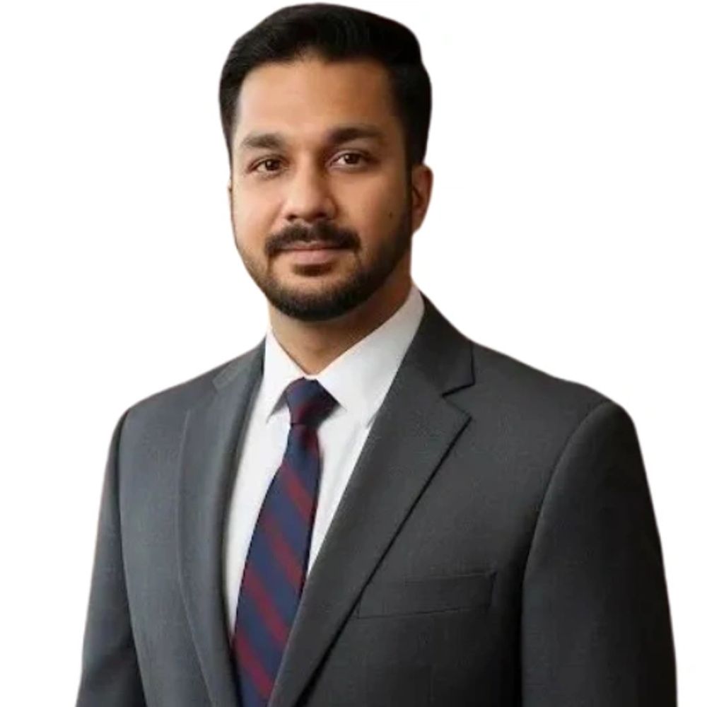 Professional man in a dark suit and striped tie against a white background.