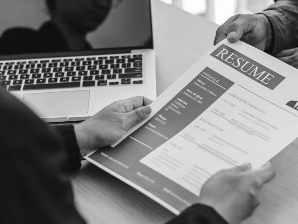 Person reviewing a resume near a laptop.