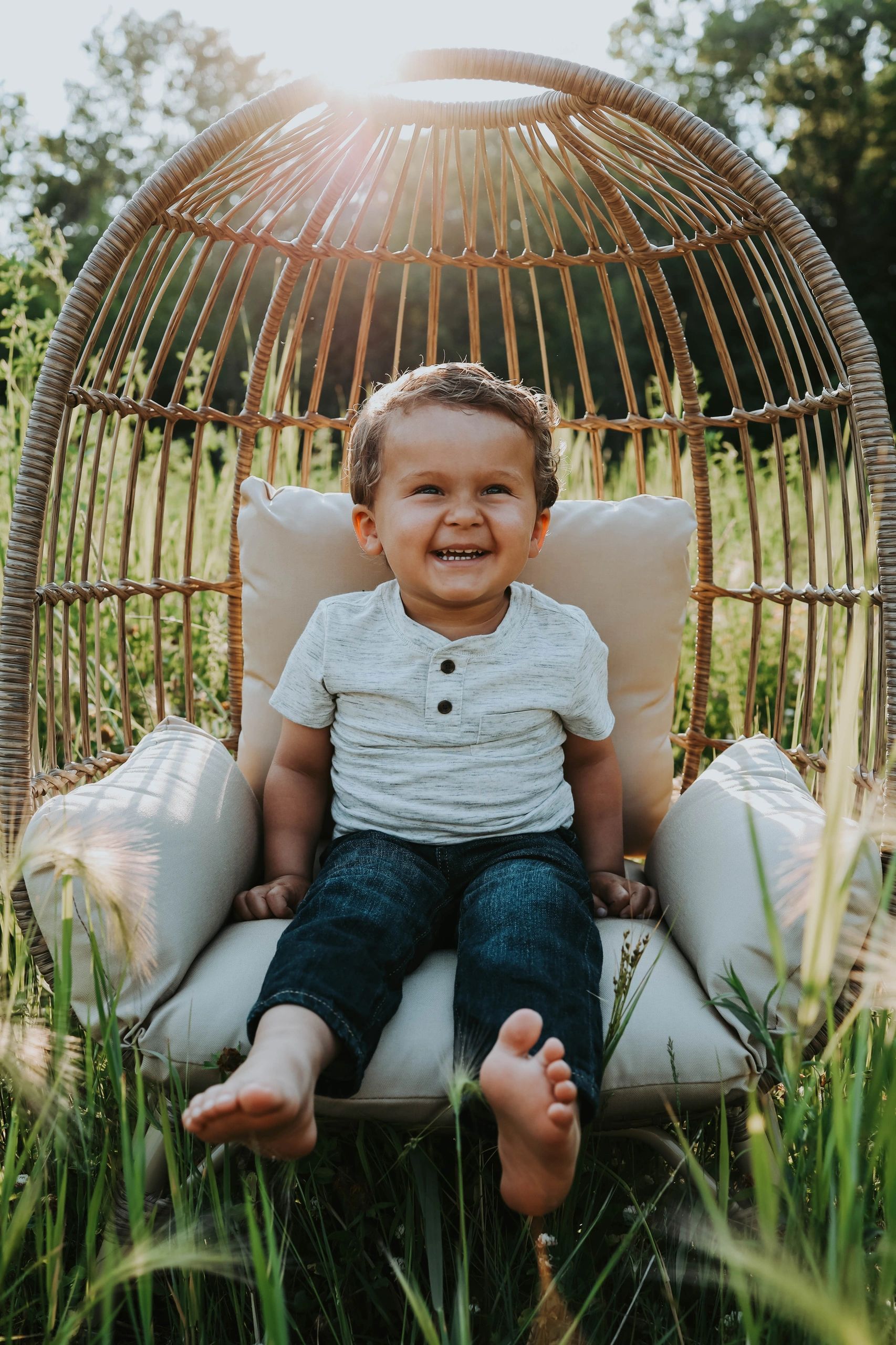 Happy toddler sitting in a wicker chair outdoors.