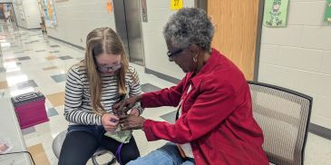 A young girl and an elderly woman knitting together.
