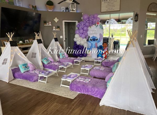Indoor kids' slumber party setup with teepees and purple bedding.