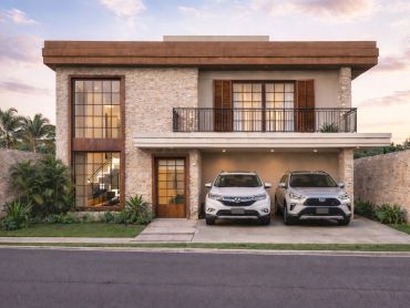 Modern two-story house with stone facade and two parked cars in the driveway.