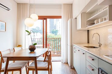 Bright modern kitchen with wooden dining table and large window.