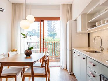 Bright modern kitchen with wooden dining table and large window.