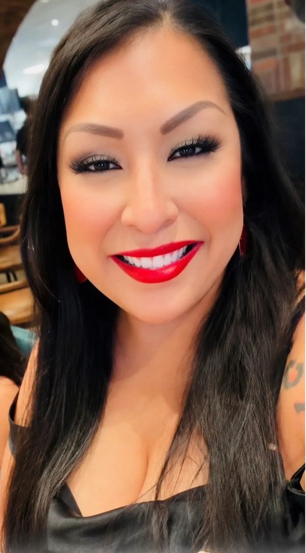 Smiling woman with long black hair and bright red lipstick.