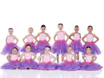 Young ballerinas in pink and purple tutus posing together.