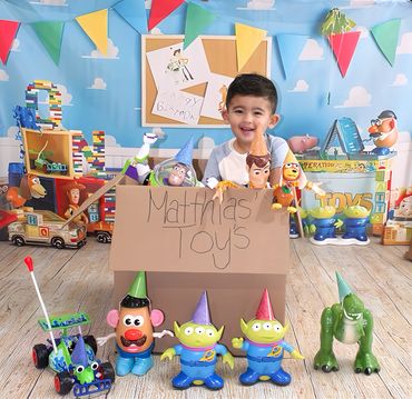 Young boy playing with Toy Story toys in a colorful room with festive flags.