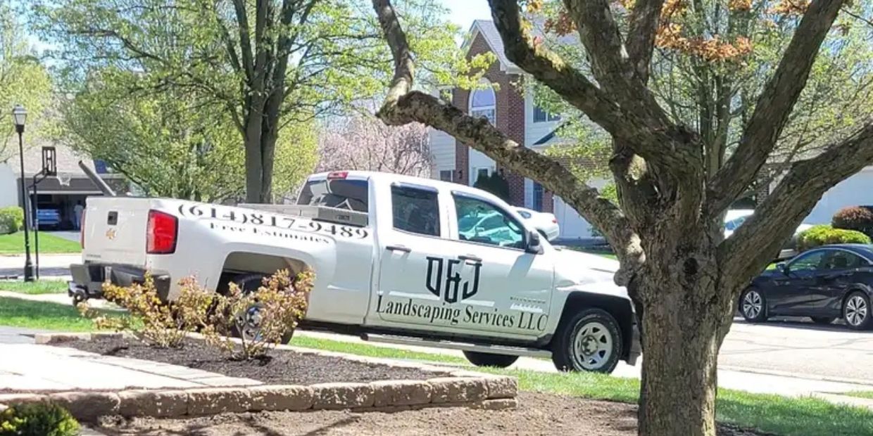 White landscaping service truck parked near a residential area on a sunny day.