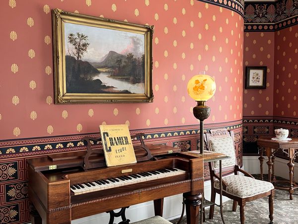 Drawing room with curved wall at the Rich-Twinn Octagon House & Hudson River school style painting.