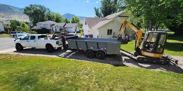 Truck pulling a dump trailer with an excavator ready to load.