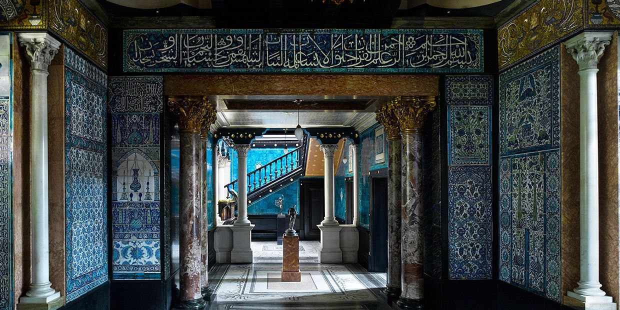 Ornate hallway with blue tilework and marble columns in classic architectural style.